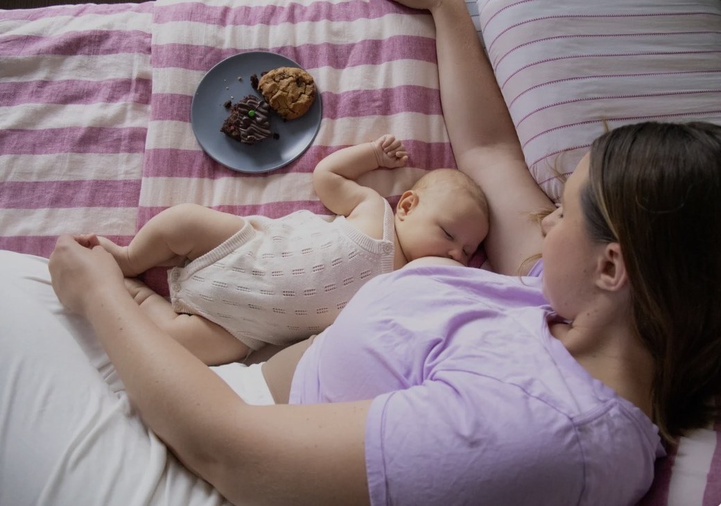 Ash resting with her newborn beside Milk and Bloom lactation treats