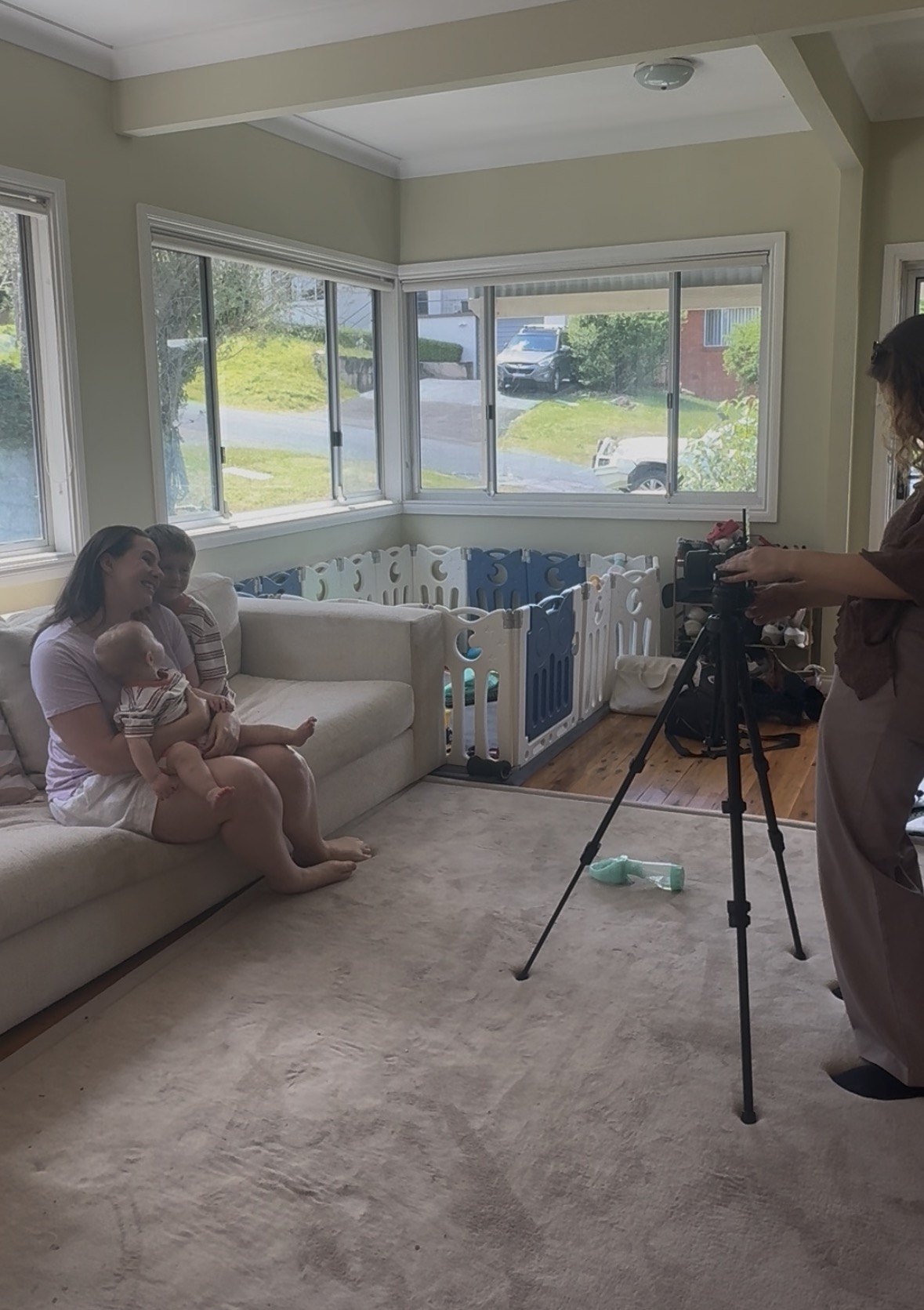 Ash on a couch with her two children while a videographer films a content shoot